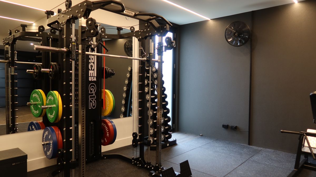 Functional trainer and dumbbell tower against a charcoal feature wall