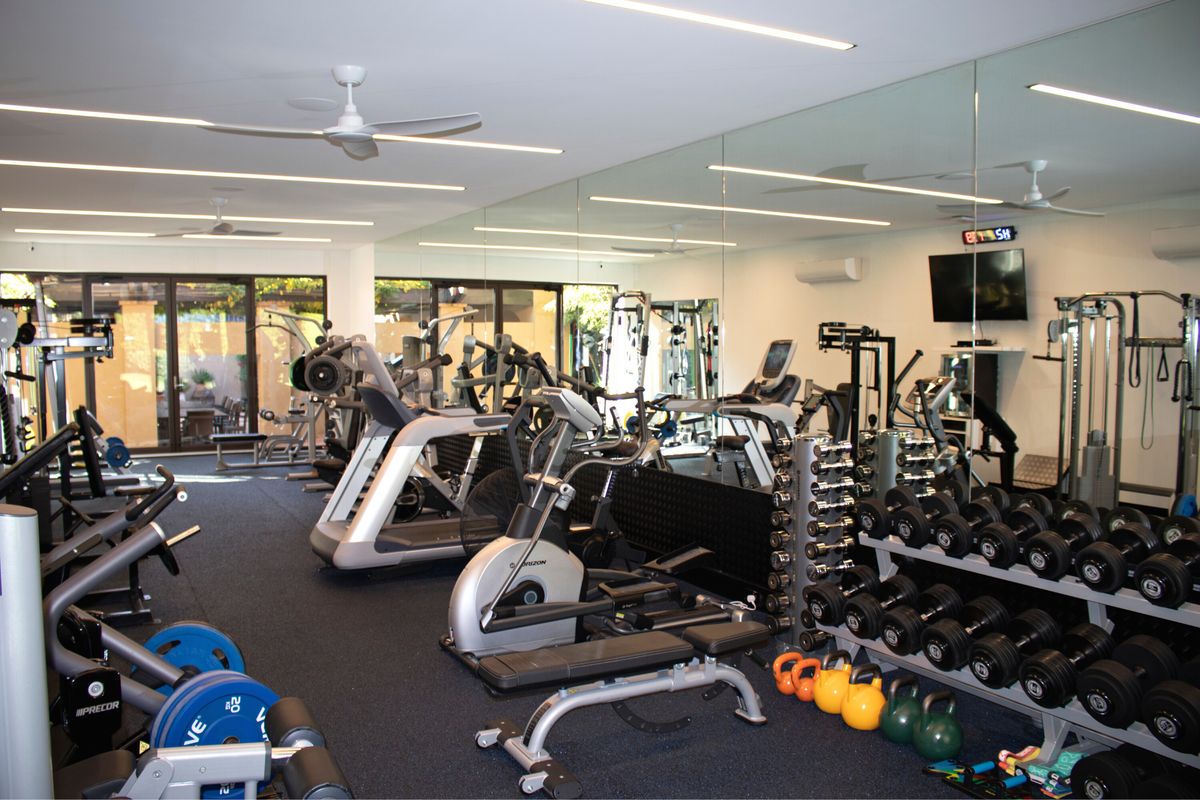 Large private gym with cardio machines, dumbbells and mirror wall